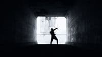 a person standing in a dark tunnel with their arms in the air