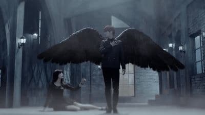 a man standing next to a woman with large wings