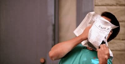 a man is covering his face with a piece of paper
