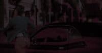 a man walking past a red car on a city street