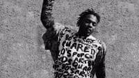 a man with dreadlocks standing in front of a wall