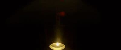 a lit candle in a dark room with a black background