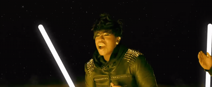 a woman in a leather jacket holding two lightsabes