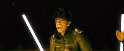 a woman in a leather jacket holding two lightsabes