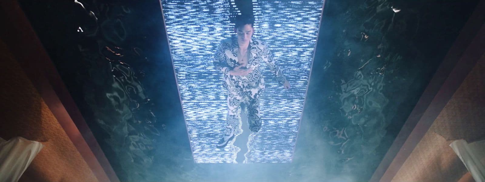 a giraffe standing in a room with a blue light coming from the ceiling