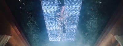 a giraffe standing in a room with a blue light coming from the ceiling