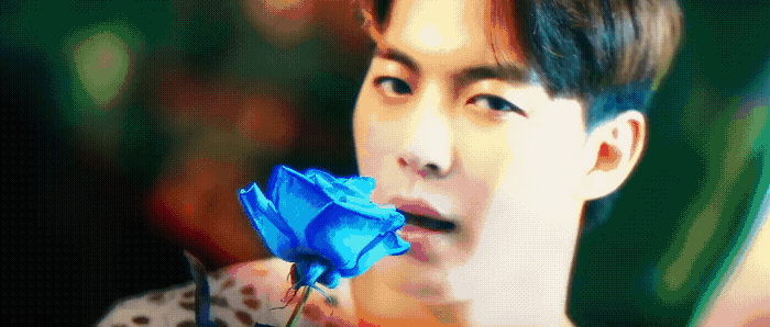 a man holding a blue rose in his hand