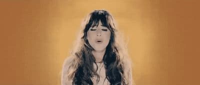 a woman with long hair standing in front of a yellow background