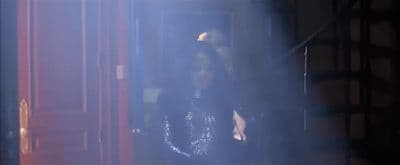 a woman standing in a doorway in a dark room