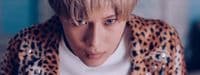 a man with blonde hair wearing a leopard print jacket