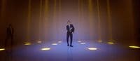 a man in a suit standing in front of a wall of lights
