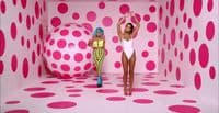 two women standing in front of a pink polka dot wall