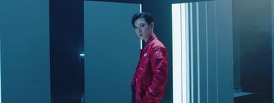 a man in a red jacket standing in front of a mirror