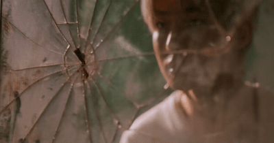 a man holding a broken umbrella in front of a mirror