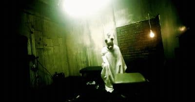 a man in a white robe standing in a dark room