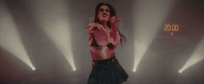 a woman in a pink shirt and black skirt on stage