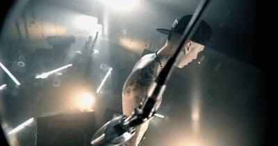 a man in a black hat is holding a guitar