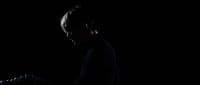 a man standing in the dark with his hand on his head