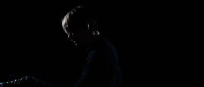 a man standing in the dark with his hand on his head