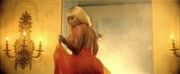 a woman in a red dress standing in front of a mirror