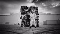 two people standing in front of a giant stack of tires