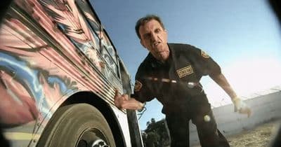 a man in a police uniform standing next to a car