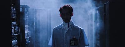 a man in a lab coat standing in a dark room