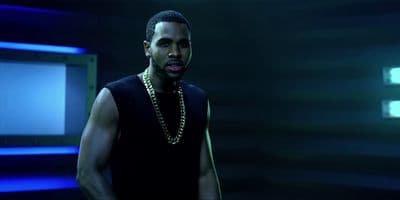 a man in a black tank top standing in a dark room