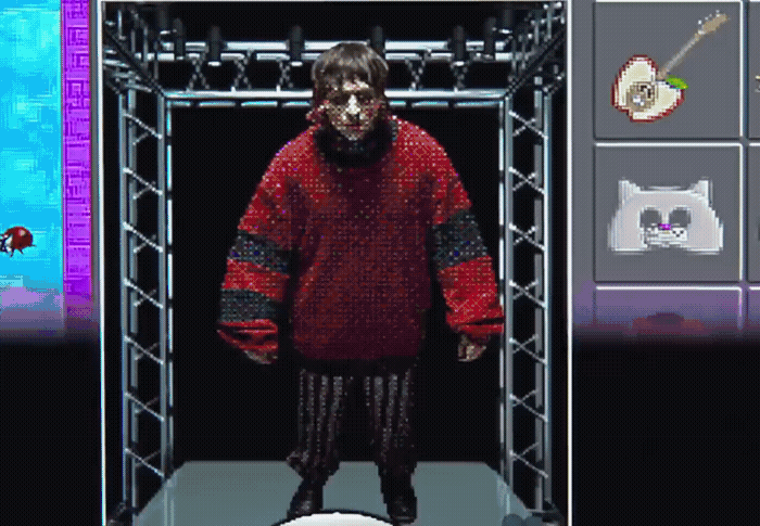 a man in a red sweater standing in front of a screen