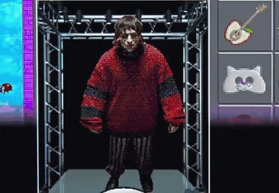 a man in a red sweater standing in front of a screen