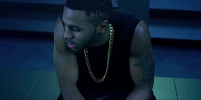 a man sitting on the ground with a chain around his neck