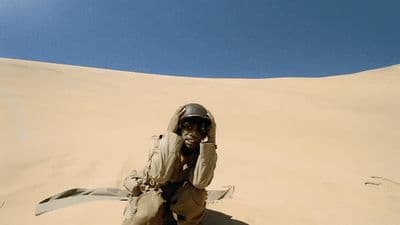 a man sitting on top of a sandy dune