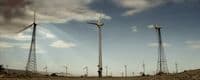 a group of windmills on a hill under a cloudy sky