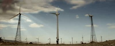 a group of windmills on a hill under a cloudy sky