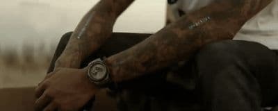 a man with tattoos sitting on a chair