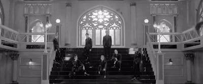 a black and white photo of a group of people sitting on a set of stairs