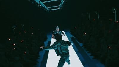 a man walking down a runway in a dark room