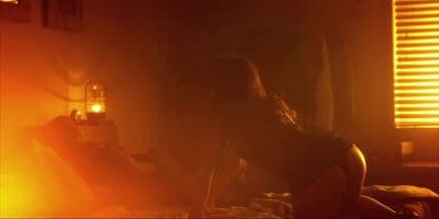 a naked woman sitting on a bed in a dark room