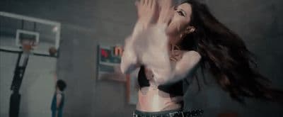 a woman in a black bra top standing in front of a basketball hoop