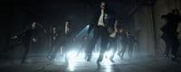 a group of men in suits and ties dancing in the dark