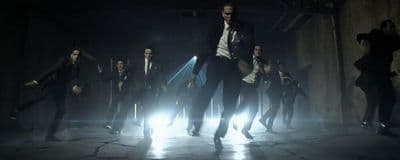 a group of men in suits and ties dancing in the dark