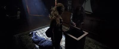a woman standing in a dark room with a suitcase