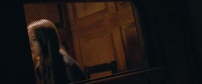 a woman standing in front of a window in a dark room