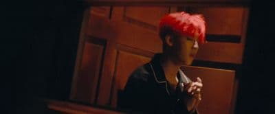 a man with a red mohawk sitting on a bench