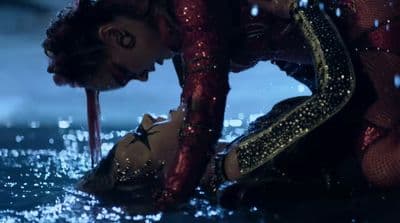 a woman in a wet suit kneeling down in the water