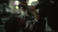 a woman getting her hair cut by a man