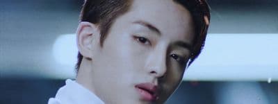 a close up of a person wearing a suit and tie
