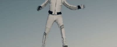 a man in a white suit standing on a snowboard