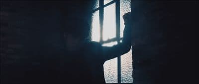 a person standing next to a window in a dark room