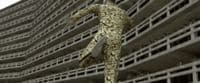 a man in a suit jumping in front of a building